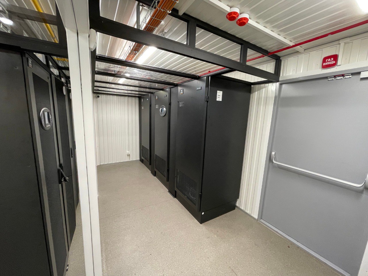 Interior of indirect free cooling modular data center with UPS cabinets, server racks, gas fire suppression system, and overhead cable trays
