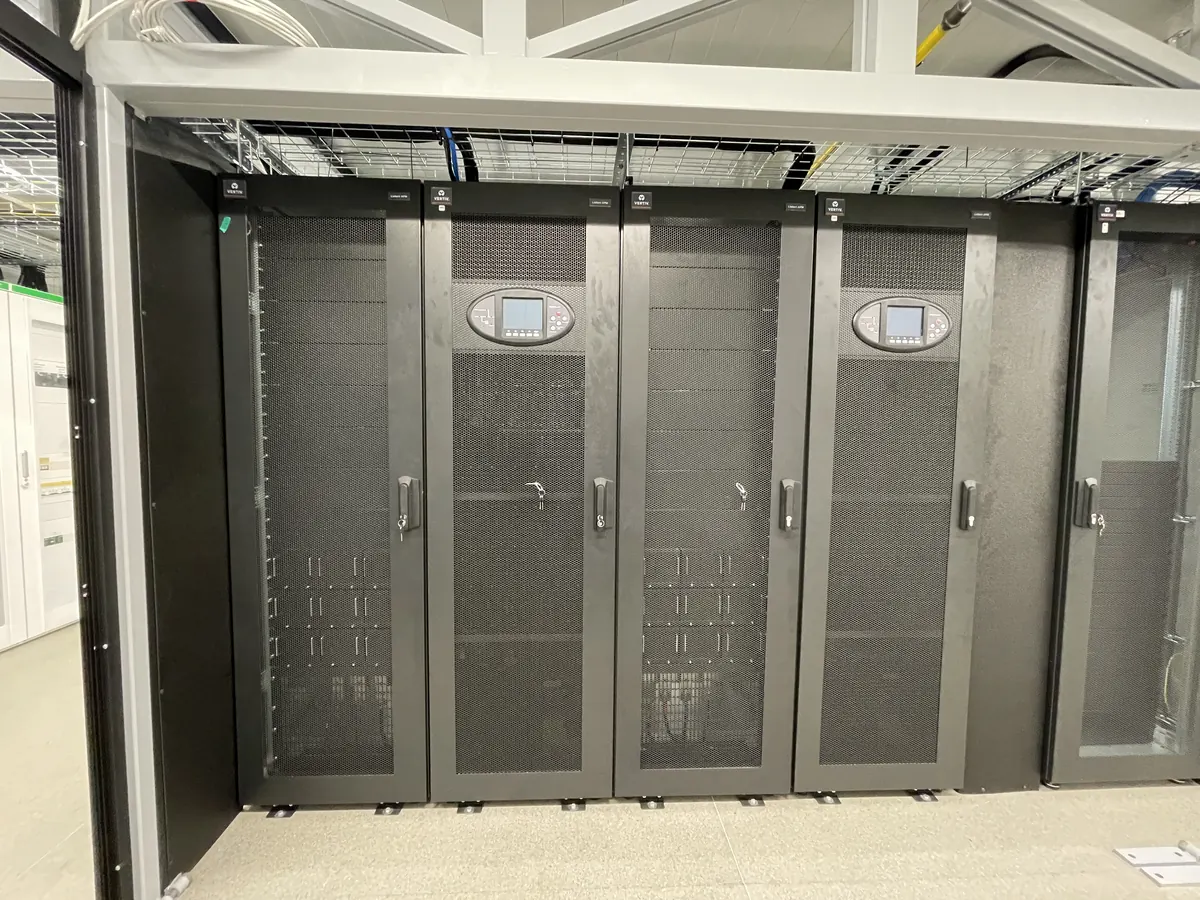 A row of server racks with perforated doors inside a module
